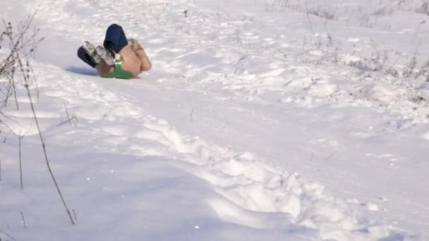 Flicka rullar nedför backen i släde i snö. Flicka leker på vintern i parken. — Stockvideo