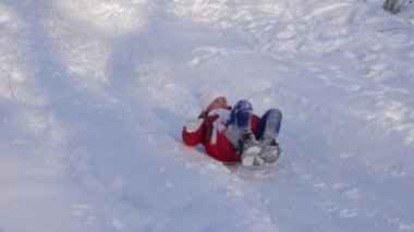 mutlu çocuk kar kızağı slaytta slaytlar ve elini dalgalar. küçük kız parkta kışın oynuyor