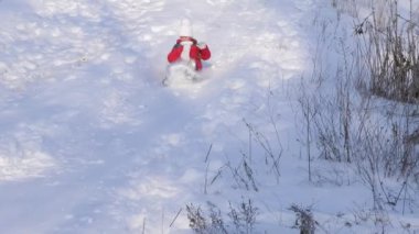 Kız kızakta tepeden aşağı yuvarlanıyor. Kar çocuk yüzüne gider, mutlu kız parkta kışın oynar. Ağır çekim