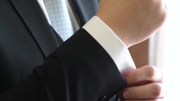 Mannen i blå slips och svart kostym rätar hylsa av vit skjorta. — Stockvideo