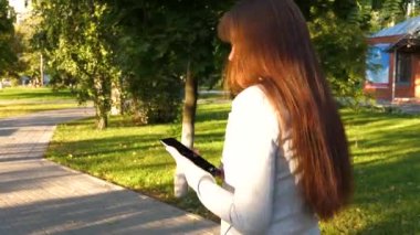 tablet hafif iş takım elbiseli kızla işe gidiyor. güzel iş kadını sokakta park tablet ile birlikte onun elinde yürür.