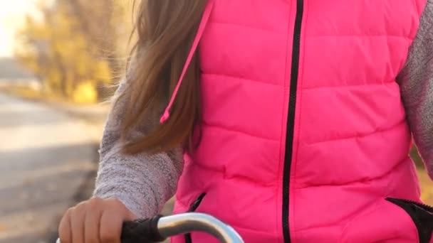 Handen van meisje houdt gebogen fiets stuur. Meisje paardrijden fiets en lachend in de herfst park. Close-up — Stockvideo