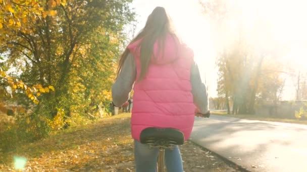 Dítě jede ulicí na kole v záři zapadajícího slunce. Zpomalený pohyb. — Stock video