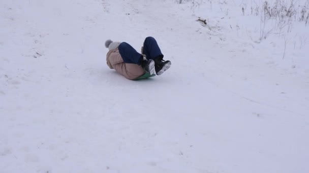 Chica joven montando colina de nieve en trineo en las vacaciones de Navidad . — Vídeos de Stock