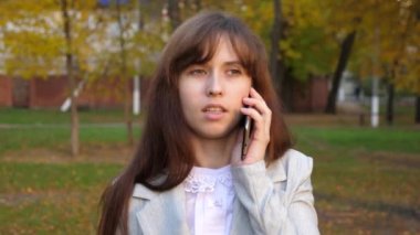 smartphone üzerinde konuşmak ve gülümseyen güzel kadın. kız cep telefonu üzerinde konuşurken ve şehir parkında akşam yürüyüş