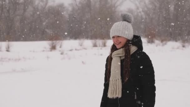 Mooi meisje meisje wandelingen in winter park in de sneeuwval. — Stockvideo