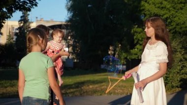 Anne ve çocuklar büyük sabun köpüğü Şehir Parkı ve gülümseme olun. Ağır çekim.