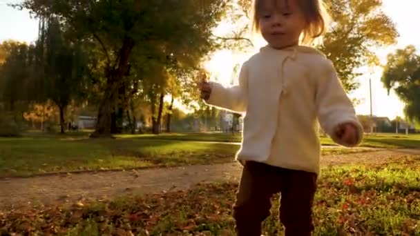 Feliz bebé caminando por la noche en la calle. niño pequeño corre en el parque de otoño en césped y hierba seca . — Vídeos de Stock