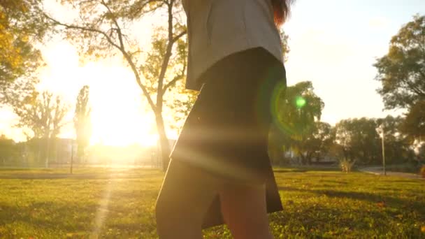 Belas pernas de mulher de negócios andando pela calçada. close-up. mulher de negócios na saia caminha no parque em raios de belo pôr do sol com preto — Vídeo de Stock