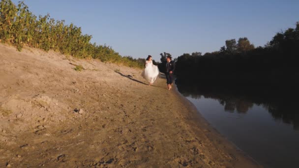 Feliz novia y novio correr descalzo en la playa a lo largo del río — Vídeos de Stock