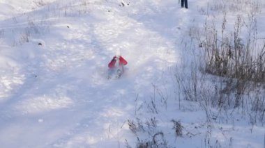 mutlu çocuk karla kaplı yüksek hız treni ile kızak sürmek, kar sinek kızlar yüz içine su sıçramalarına. Aile Noel tatili kış parkta.