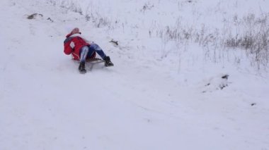 Mutlu kız kış ve gülümser üzerinde beyaz kar kızakta karlı dağdan alır. Noel tatili. Ağır çekim