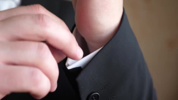 Hombre con corbata azul y chaqueta negra endereza la manga de una camisa blanca. primer plano — Vídeos de Stock