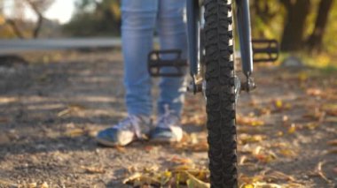bisiklet tekerleği ile yürümek, yakın çekim. kızın bacaklarını yollara ve bisiklet rulo.