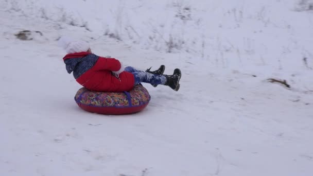 Fiatal lány csúszik egy cső lecsúszik. boldog gyermek játszik a karácsonyi park. Lassú mozgás. — Stock videók