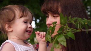 Anne ve çocuk yeşil yaprakları ağaçların sıcak yeşil park içinde arıyoruz.