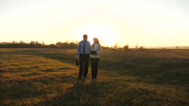 Hombre de negocios con maletín y mujer de negocios con tableta están de acuerdo en trabajar juntos al atardecer y reír. Reunión de negocios con el socio de trabajo — Vídeos de Stock