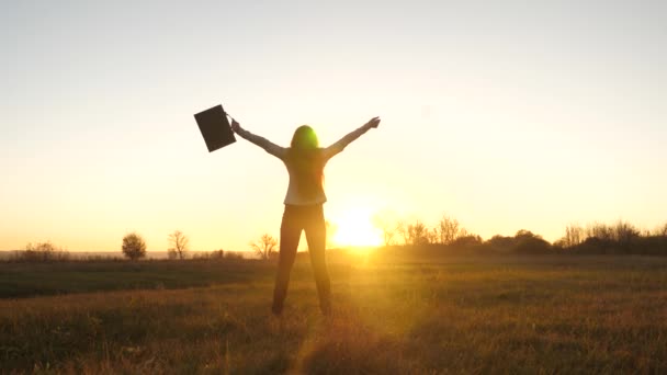 Mujer de negocios libre con maletín en la mano y en traje de negocios es el éxito al atardecer en los rayos brillantes del sol — Vídeos de Stock