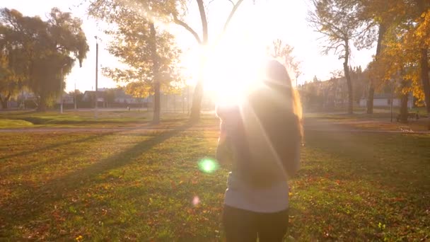 Business woman with small child walking through city park in sunset rays of sun. — Stock Video