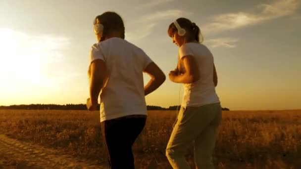 Nastolatki są zaangażowane w Sport bieganie na drodze słuchanie muzyki na słuchawkach — Wideo stockowe