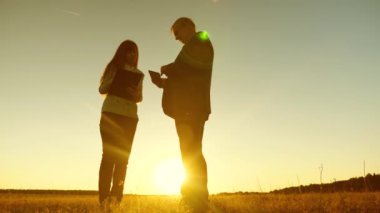 İş adamı ile tablet tablet ve iş kadın ile tartışmak plan ve program günbatımı ve gülüyor. İş toplantısı çalışma ortağı ile