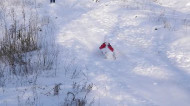 Kız kırmızı ceket ve beyaz şapka atkı ile yüksek karlı dağdan sürmek kar aşağı yan yatan. Kış tatili