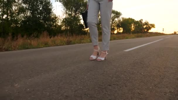 Mujer de negocios lleva maletín negro con documentos en la mano. Las mujeres piernas en zapatos blancos y pantalones van en asfalto — Vídeos de Stock
