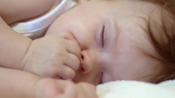 Kis baba alszik a gyerekágyban, és tartja a kis kezét öklével — Stock videók