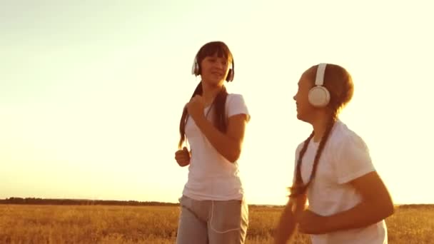 Tonårsflickor i hörlurar är engagerade i jogging, skrattar och ler vid fysisk ansträngning. Slow motion — Stockvideo