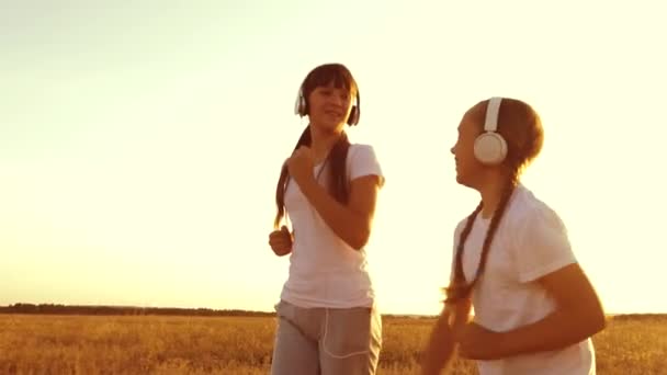 Las adolescentes con auriculares se dedican a trotar, reír y sonreír durante el esfuerzo físico. Movimiento lento — Vídeos de Stock