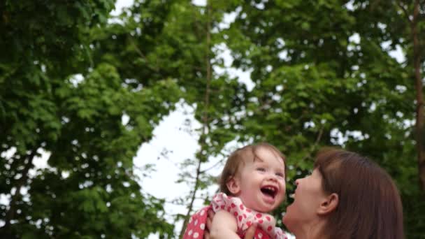 赤ちゃんは、愛情のあるお母さんの手を笑います。公園に散歩に一緒に遊んで、赤ちゃんとママが笑わせます。スローモーション. — ストック動画