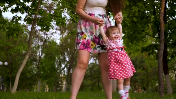 ママの手で彼女の娘を保持しているし 幸せな子供の笑い 彼女を振る 緑の芝生公園に彼女の母親と遊ぶ娘 — ストック動画
