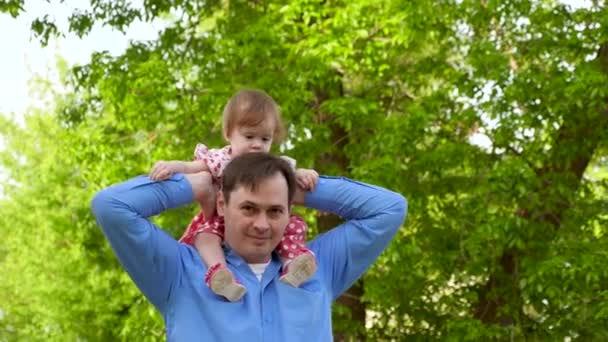 Padre lleva a la pequeña hija en sus hombros, camina en el parque de verano con un niño — Vídeo de stock