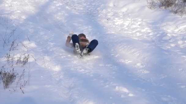 Mladá dívka jezdí v zimě na saních z vysoké zasněžené kopce. Vánoční svátky — Stock video