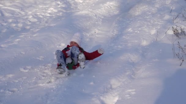 Happy girl monte traîneau de glissement de neige élevé et rit. Fille se reposant dans le parc de Noël en hiver . — Video