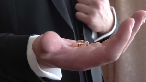 Жених держит в руке коробку золотых обручальных колец, крупным планом — стоковое видео