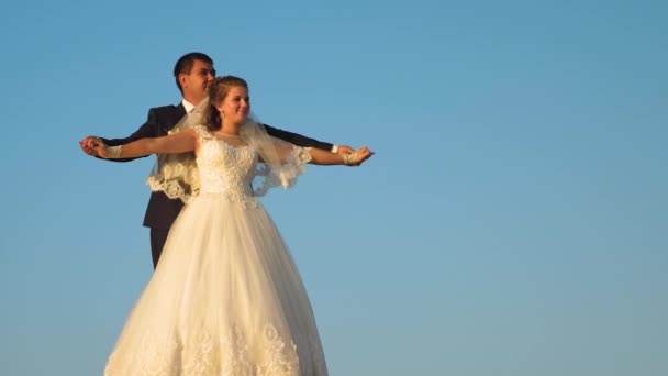 Lyckliga bruden och brudgummen i vit klänning svävar över blå himmel och ler. — Stockvideo