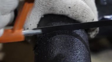 bir demir testeresi ile beyaz koruyucu eldiven testere siyah tüp işçi. yakın çekim