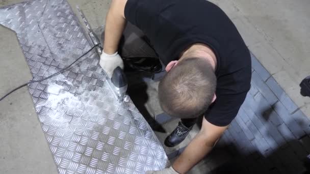 Operaio in vetri protettivi sega una lamiera di ferro lucido con una sega giga elettrica in guanti protettivi bianchi. vista dall'alto — Video Stock