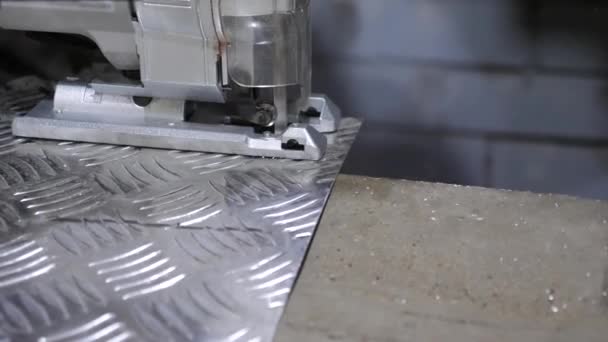Het snijden van een glanzende ijzeren plaat met een elektrische puzzel. Close-up — Stockvideo