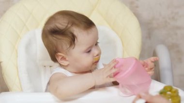 küçük çocuk Çocuk koltuğuna oturur ve Childs'ın cam suyu içer