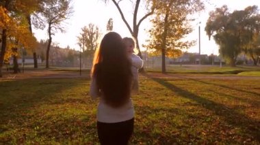 Anne küçük çocukla parlak güneş gölge tarafından tarihi bir şehir parkta yürüyüş