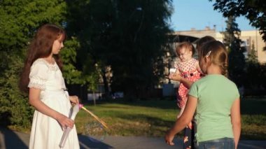 Anne ve çocuklar büyük sabun köpüğü Şehir Parkı yapım ve gülüyor. Ağır çekim