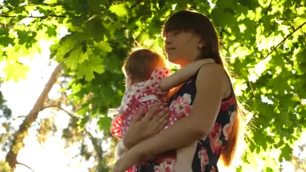 Молодая мама обнимает маленькую дочь, целует и улыбается — стоковое видео