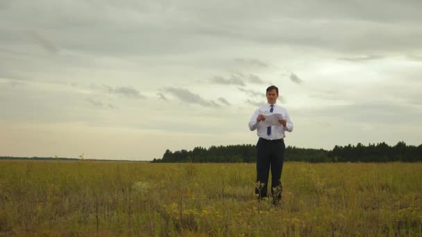Бизнесмен в белой рубашке и синем галстуке бросает документы в поле — стоковое видео