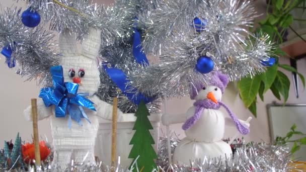 Handgemaakt Christmas speelgoed onder de kerstboom Haas en sneeuwpop. Zilveren kerstboom in de kinderkamer is versierd met blauwe ballen kerstversiering. — Stockvideo