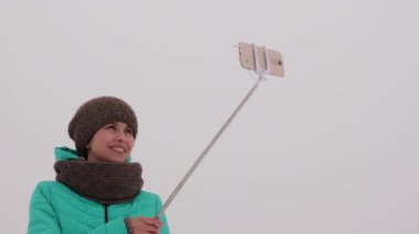 kız akıllı telefon ve selfie zamanında fotoğraflandı. parkta yavaş yavaş kar kış aylarında düşer