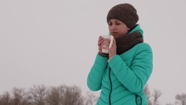 Girl drinks hot tea in the park in winter. — Stock Video