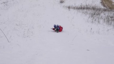 mutlu genç kız kış parkta kızak üzerinde bir yüksek karlı tepeden geliyor. Kız gülüyor ve sevinir.