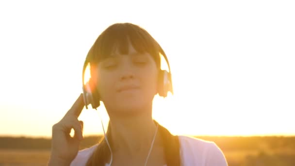 Mladá dívka v sluchátka chůzi po silnici poslouchá hudbu a tanec — Stock video
